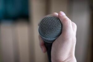 Hand holding a microphone on blur background photo