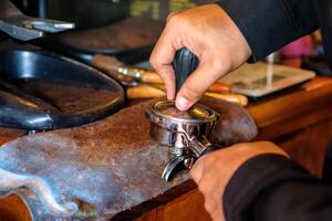 Hand barista tamper pressing powder coffee in grinder photo