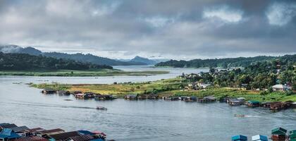 sangkhlaburi balsa pueblo en represa y barco navegación ver el cultura en lluvioso temporada foto