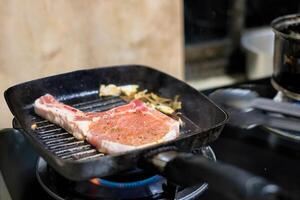 Raw meat steak on black pan with grill garlic photo