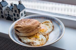 Hamburger bun scorched with fried eggs in plate photo