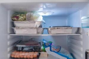 abierto refrigerador lleno con crudo alimento, vegetales y frustrar paquete foto