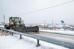 Yellow snowplough plowing on snowy road photo