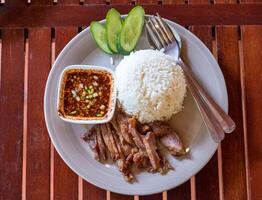 Grilled sliced pork with jasmine rice on wood table photo