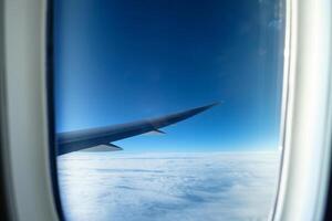 Window of aircraft wing with white cloud on sky photo