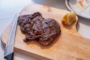 Medium rare Beef grilled with lemon slice on wood chopping block photo