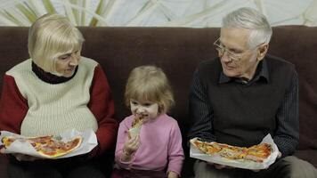 Beautiful elderly man and woman eats pizza with their granddaughter video