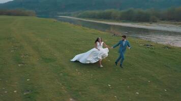 Wedding couple running near mountain river. Groom and bride. Arial view video