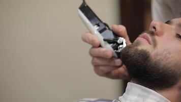 Client with black beard during beard shaving in barber shop. Groom, masculine video