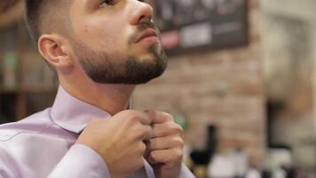 Groom adjusts the shirt in barbershop background. Preparing to go to the bride video