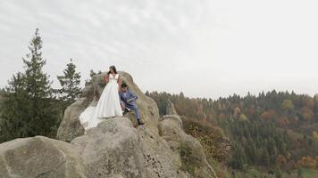 Novelli sposi In piedi su un' alto pendenza di il montagna. sposo e sposa video