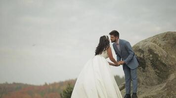 Newlyweds stand on a high slope of the mountain. Groom and bride video