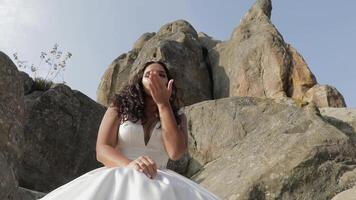 la mariée asseoir sur une haute pente de le Montagne. heureux. dansant et fabrication visages video