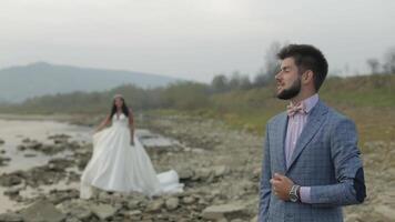 Wedding couple standing near mountain river. Groom and bride in love video