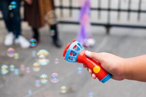 Hand pressing blower toy of bubbles soap on air photo