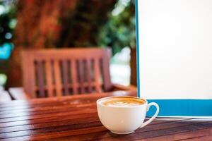 blanco café latté taza con blanco letrero en de madera escritorio foto