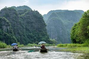 Activity downstream in mountain valley on boat with vietnamese using foot paddle in Ngo Dong river, Ninh Binh photo