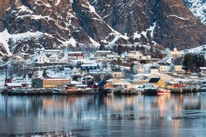 Traditional scandinavian fishing village and mountain on coastline in Norwegian sea on winter at Lofoten Islands photo