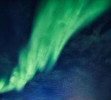 Bright and active Aurora borealis or Northern lights glowing in the night sky on Arctic circle photo