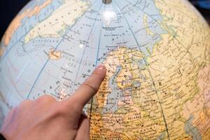 Finger pointing on world ball for planning travel trip photo