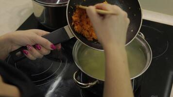 Adding grated carrot into saucepan with soup with potato and fish video