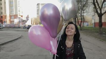 Söt kvinna gående längs de gata innehav ballonger med helium video