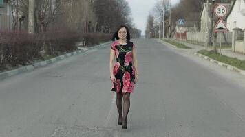 attrayant Jeune femme dans une robe avec fleurs en marchant sur le Autoroute video