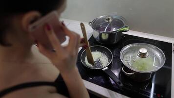 Beautiful caucasian woman talking on the phone while cooking video