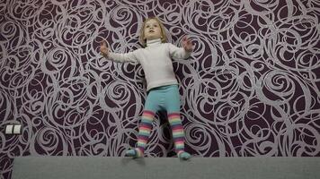 Little happy child walking and dancing on sofa and listening music. Slow motion video