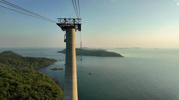 Aerial view of a cable car system with a large pillar over tropical islands and sea, suggesting adventure tourism or transportation video