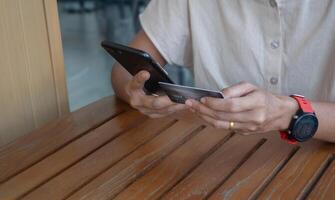 mujer sentado en silla a al aire libre el café participación crédito tarjetas y utilizando teléfono inteligente a compras en línea pagos, internet bancario aplicaciones y comercio electrónico foto