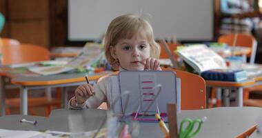 fille dessin à le table dans Salle de classe. éducation. enfant séance à une bureau video