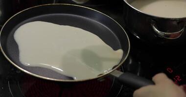 The process of cooking homemade pancakes. Woman pours pancake dough on pan video