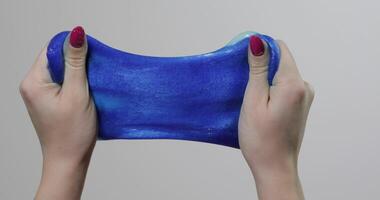 Woman hands playing with oddly satisfying blue slime gooey substance. Antistress video