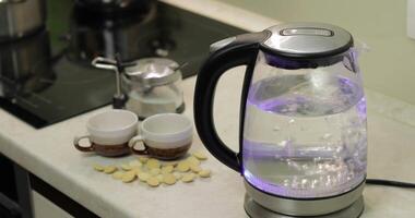 Tea kettle with boiling water. Tea bags and sugar on the background video