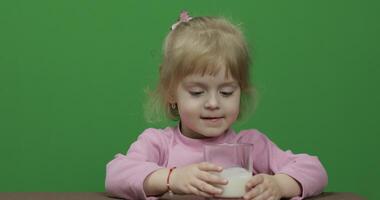 meisje zittend Bij de tafel en drankjes yoghurt melk. grappig melk snor video