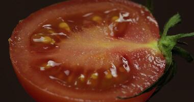 Rotate of the halves of fresh ripe cut tomato on a dark background video