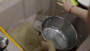 Child washing dishes in the kitchen. Close up of girls hands video