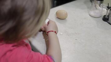 fechar-se do uma pequeno menina limpa a Concha com uma fervido frango ovo video