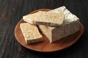 Sliced Tempeh, Fermented Soybean. Servde on Wooden Plate photo