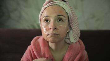 mulher assistindo uma atrasado noite filme às televisão, comendo Pipoca. roupão de banho, facial mascarar video