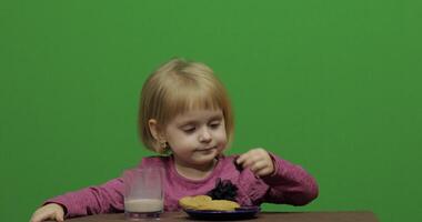 Girl sitting at the table and eating chocolate, cookies and drinks cacao video