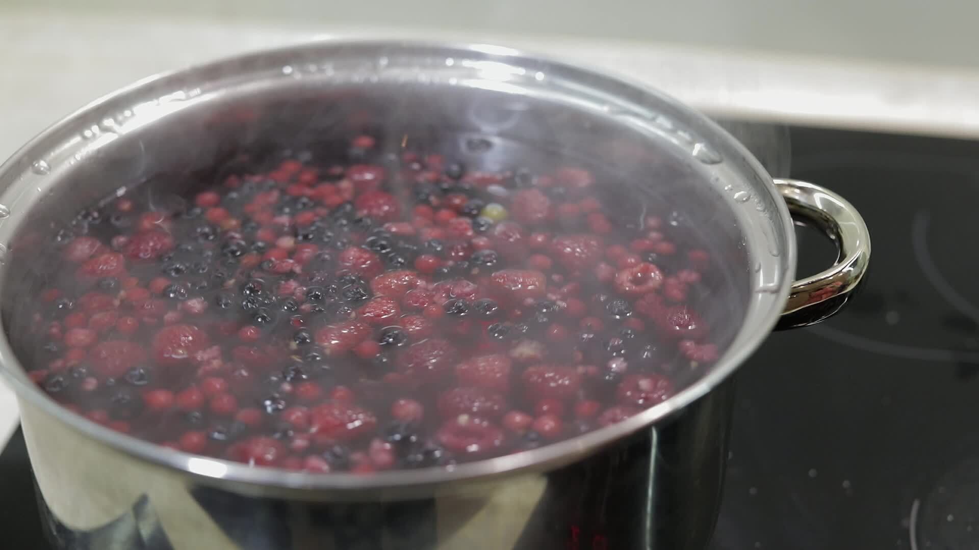 Stir the berries in pot with boiling water. Cooking compote. Kitchen