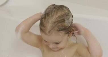 Attractive three years old girl takes a bath. Cleaning and washing hair video