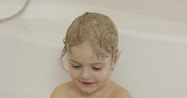 Attractive three years old girl takes a bath. Cleaning and washing hair video