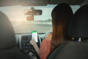 Driver using GPS navigation in mobile phone while driving car at sunset photo