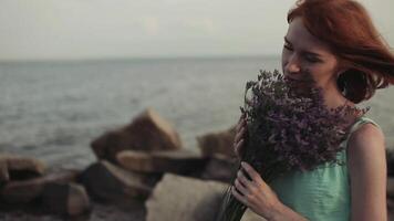 langzaam beweging. mooi jong sexy meisje met lang rood haar- in een turkoois jurk is staand met een boeket van bloemen in haar handen. romantisch humeur video