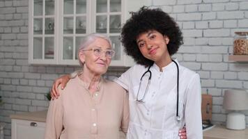 afro americano donna medico e paziente anziano donna in piedi e sorridente a casa. famiglia medico, paziente sostegno, Aiuto a casa, cura per il malato. video
