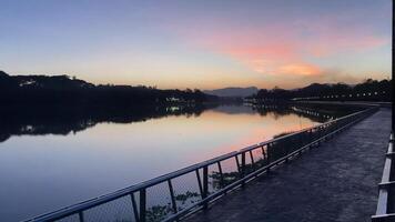 Waterside exercise walkway, A peaceful boardwalk beside a calm lake at sunset video