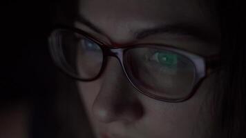 jong aantrekkelijk meisje in bril is gebruik makend van een laptop terwijl aan het liegen Aan de bed. nacht schot. 4k video